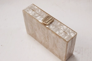 Detail view of pearlescent acrylic evening clutch with premium gold rectangular clasp