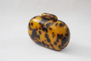 Close-up of leopard print acrylic round clutch bag with polished tortoise shell texture
