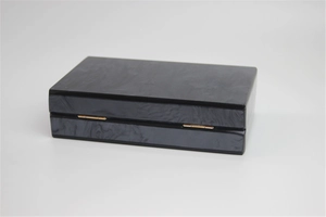 Detail of acrylic evening clutch with black marble texture and gold metal hinge
