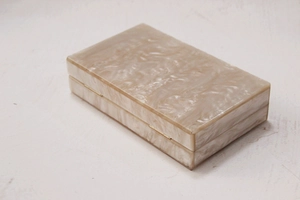 Detail view of pearlescent acrylic clutch bag featuring gold hinges and marble texture