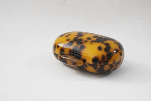 Detail of round acrylic clutch bag with retro leopard print pattern and glossy resin finish
