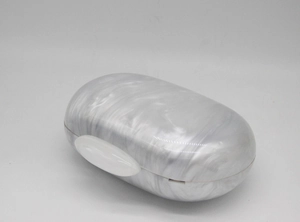 Detail of round white acrylic evening bag featuring marble texture and oval clasp
