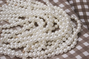 Elegant white pearl handbag chain straps with golden beads on a plaid fabric background