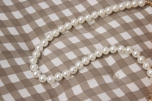 Elegant white pearl chain strap for women's crossbody bags on checkered background