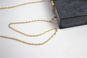 Detail of black marble pattern acrylic clutch bag with golden chain and metal clasp