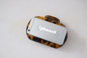 Macro detail of round leopard print acrylic clutch bag showing glossy texture and size scale