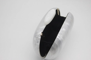 Detail view of white marble acrylic evening clutch showing black lining and gold hinges