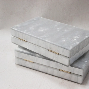 Elegant grey marble pattern acrylic clutch bag with gold metal hinges shown from a 45-degree angle