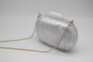 Detail of white acrylic marble texture on oval evening bag with gold chain strap