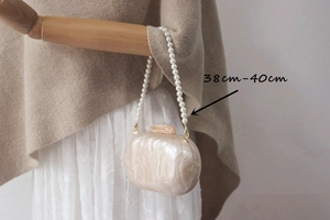 Detail of 40cm pearl bead strap on off-white marble texture evening clutch bag
