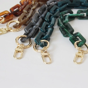 Detailed view of acrylic chain straps in leopard and tortoise shell colors with gold clasps