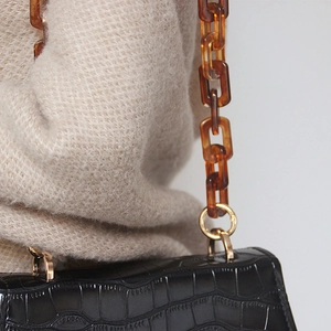 Detail of black croc-embossed bag with amber acrylic chain strap and gold hardware links