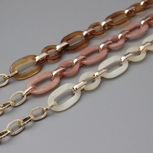 Close-up of amber, pink, and cream acrylic resin chain straps with gold metal links