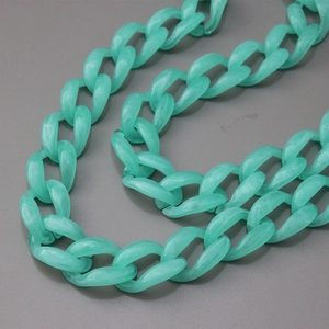 Detail of mint green acrylic resin thick chain for handbags on dark leather background
