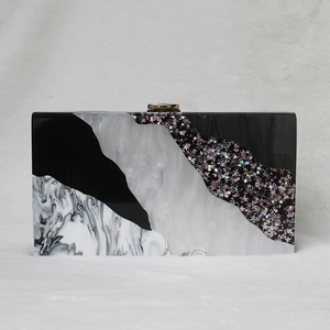 Detail of evening clutch featuring black marble pattern and acrylic sequin textures