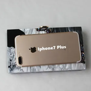 Detail showing marble acrylic clutch bag size comparison with a golden smartphone