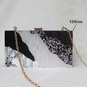 Detail of a geometric acrylic evening clutch with black white sequins and a 120cm chain