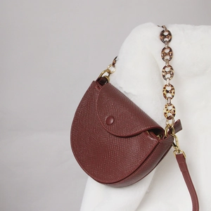 Close-up of wine red saddle bag with lizard pattern and tortoiseshell resin strap