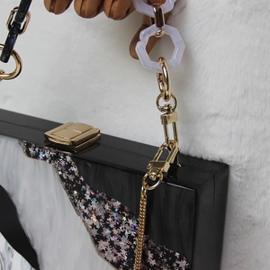 Detail of evening clutch with gold clasp and star-patterned acrylic on white fur background