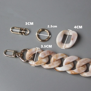 Macro detail of acrylic resin purse chain featuring marble texture and gold metal lobster clasp