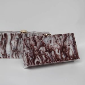 Detail of burgundy marble acrylic clutch with elegant golden rectangular clasp