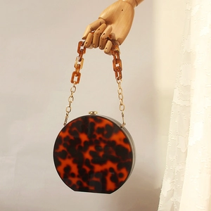 Detail einer runden Acryl-Clutch mit Schildpattmuster und eleganter goldener Kettenhandschlaufe