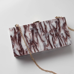 Detailed view of rectangular clutch with marble texture and golden metal chain strap