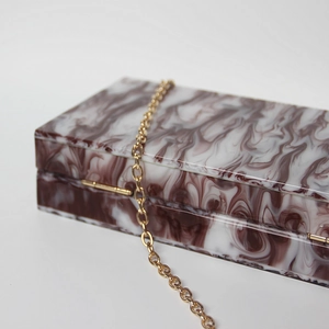 Close-up of deep purple marble pattern acrylic evening bag with gold chain strap