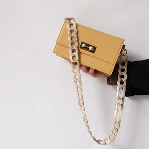 Detail of yellow clutch bag with chunky cream marble acrylic chain and pearl lock
