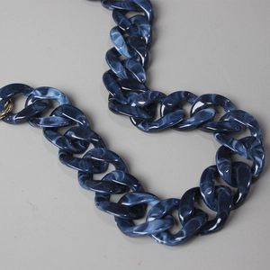Detail of dark blue marble resin chain links with gold metal rings for handbags