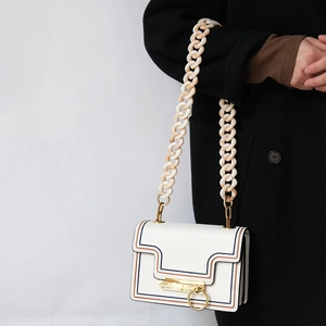 Detail of white leather shoulder bag with marble acrylic chain and gold ring clasp