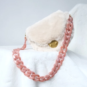 Detail view of bold pink resin chain on a soft white faux fur shoulder bag with gold clasp