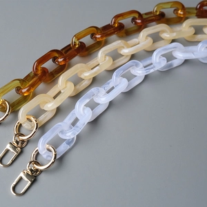 Detail of acrylic amber and marble resin chain straps with gold metal clasps for handbags