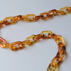 Macro view of transparent amber resin chain links for shoulder bag accessories