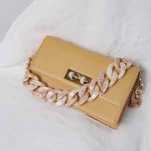 Detail of yellow leather handbag with chunky marble resin chain and pearl twist lock