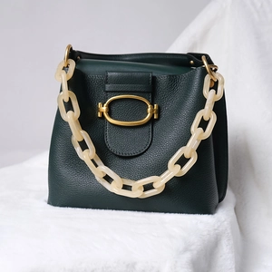Detail of dark green pebble leather handbag with marble texture resin chain handle