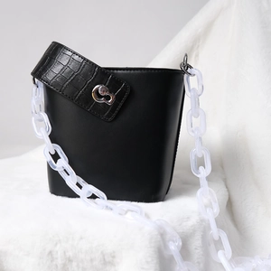 Close-up of matte black leather bucket bag with white acrylic chain and silver buckle