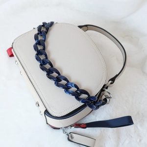 Détail de la chaîne en acrylique bleu marbré et texture du cuir sur un sac à main chic