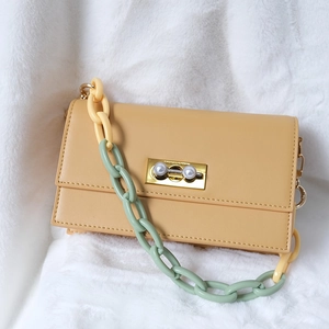 Detailed macro view of yellow flip bag with pearl gold buckle and colorful resin chain