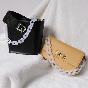 Detail of trendy acrylic resin chains on black bucket bag and beige pearl crossbody bag