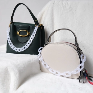 Detail of fashion handbags with white translucent resin chain straps on fur background