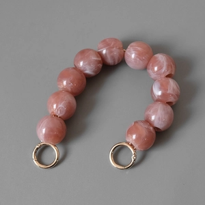 Detailansicht der rosa Harzperlen mit Marmortextur und goldenen Metallringverschlüssen