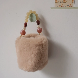 Détail du sac seau en peluche beige avec poignée en perles de résine et anneaux dorés
