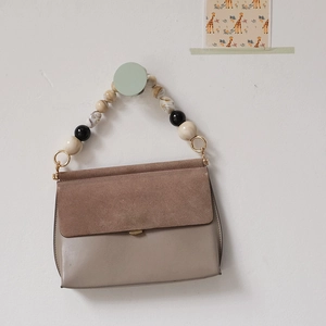 Vue détaillée de la poignée en perles de résine sur un sac à main en cuir taupe chic