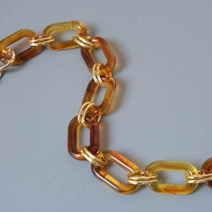 Close-up of amber resin links and gold metal rings for fashion bag straps and accessories