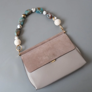 Vintage suede leather handbag with multi-color acrylic bead chain handle on gray background