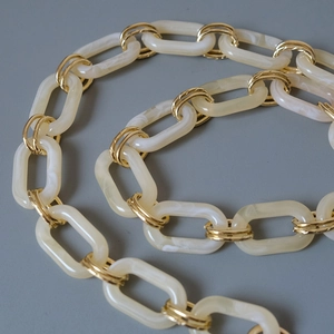 Close-up of mixed cream marble resin and gold metal link chain for fashion handbags