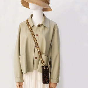 Detail showing chunky tortoise shell resin chain strap on a green coat with a mobile case