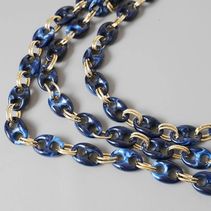 Detail of blue marble resin links and gold metal rings on a stylish shoulder strap chain
