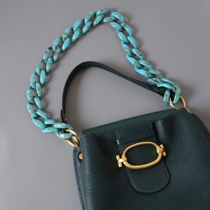 Détail du sac à main en cuir vert grainé avec bandoulière décorative en résine marbrée